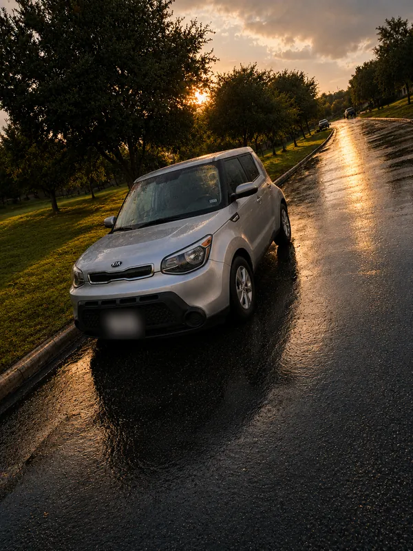 The silver Kia on a wet street at sunset
