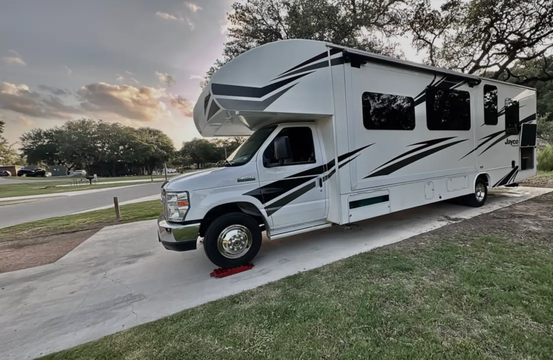 Freedom Rentals’ Class C motorhome parked on a campsite pad at dusk