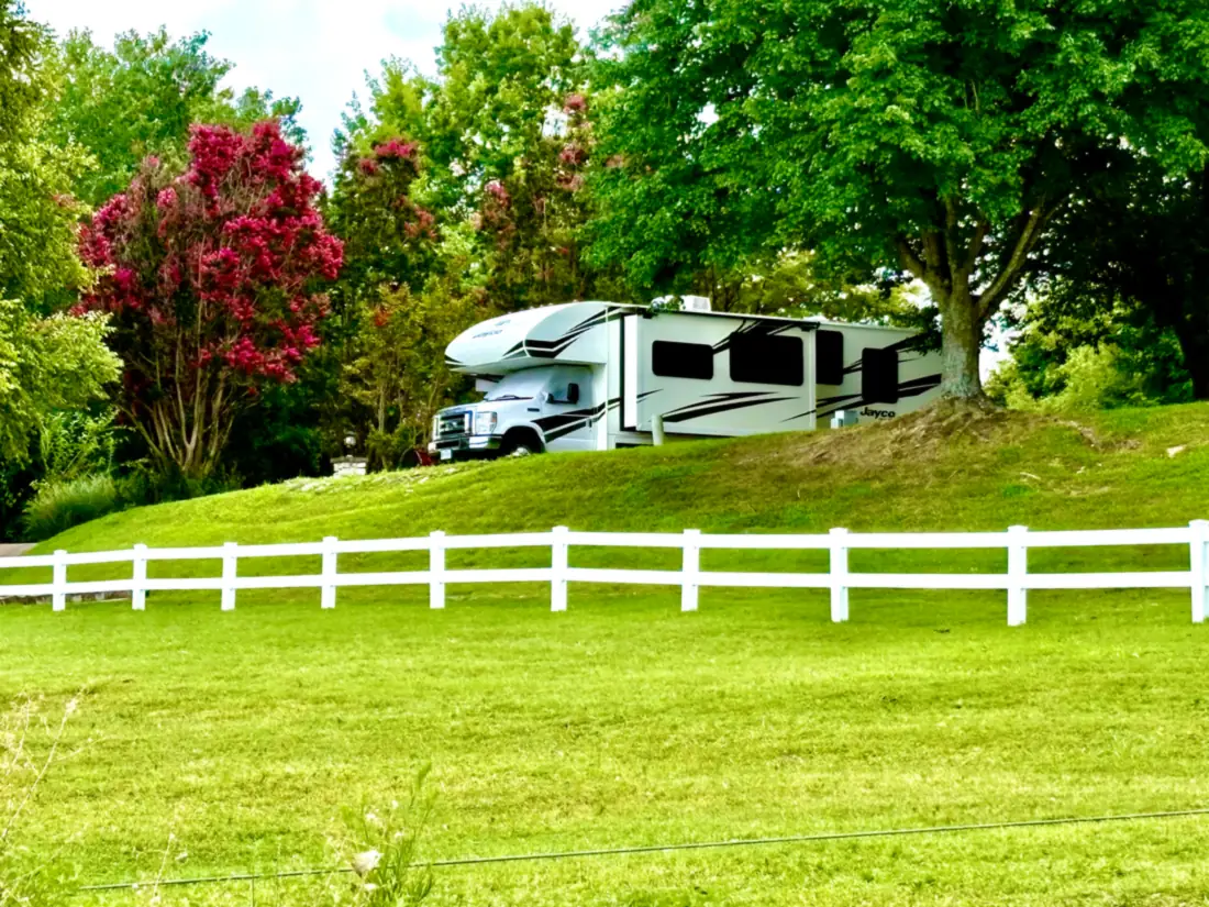 Freedom Rentals’ RV parked on a hill above a white fence in the Ozarks